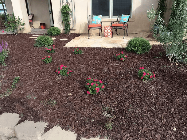 Front yard with red mulch, pink flowers, and seating area.