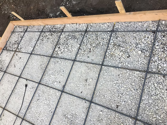 Concrete foundation with a grid of rebar within a wooden frame.