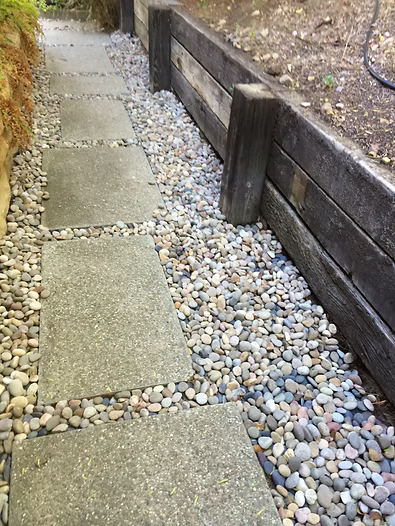 Stone pathway with gravel and a wooden retaining wall.