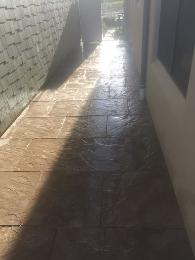 Narrow outdoor walkway with tiled floor and sunlight.