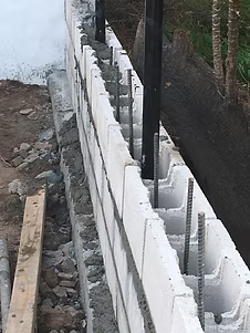 Concrete block wall construction with rebar reinforcement, outdoors.