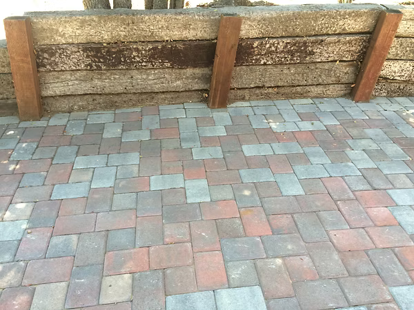 Brick patio with a retaining wall made of weathered wood.