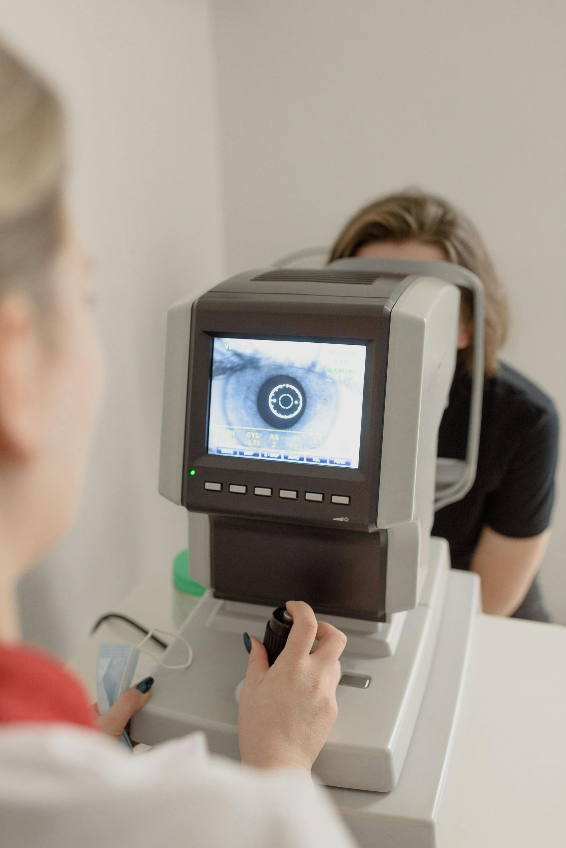 Optometrist examining a patient's eye with specialized equipment.