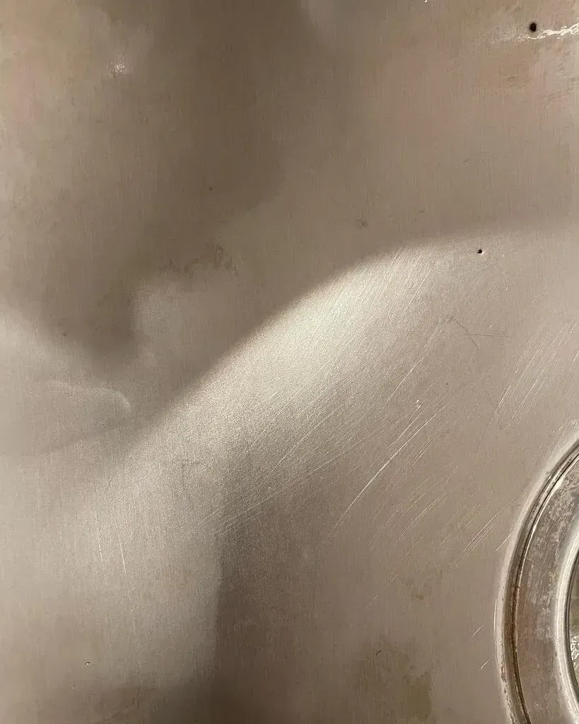 Close-up of a smooth, reflective, silver-colored metal surface with subtle curved lines and a circular edge.