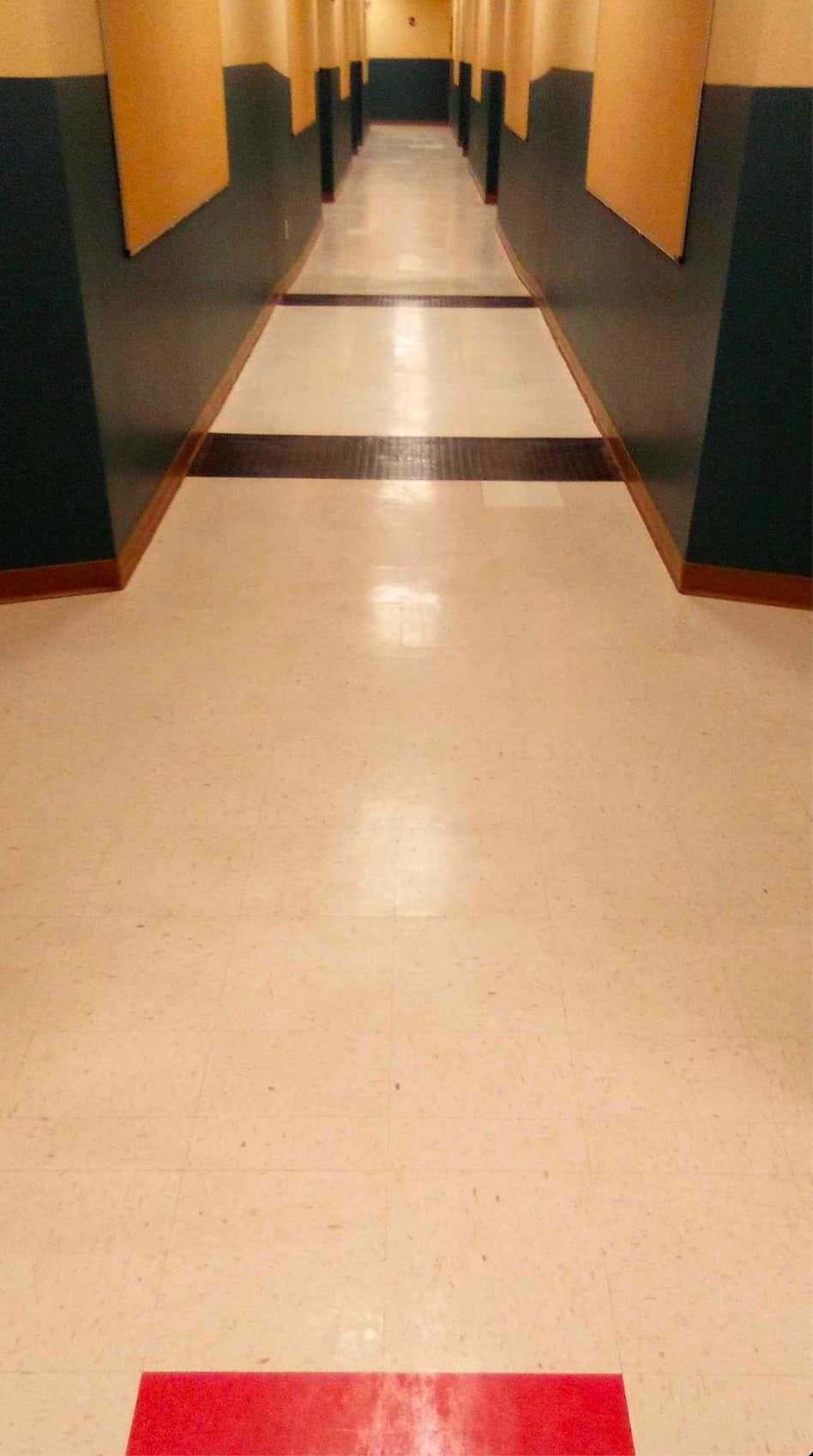 Hallway with a red strip on the floor, black and yellow walls, and rows of dark panels.