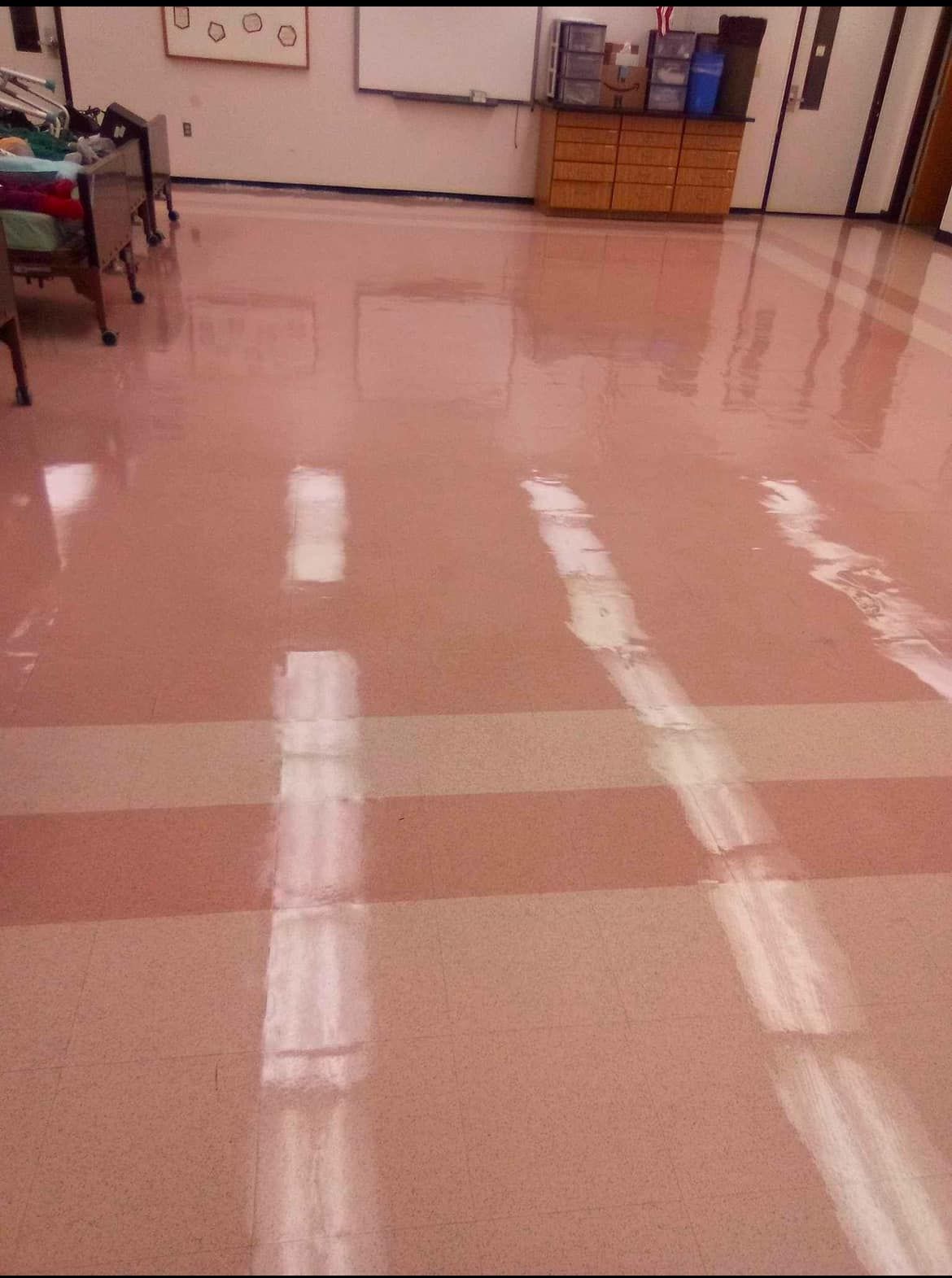 Shiny, pink-tiled floor reflecting overhead lights in an empty classroom.