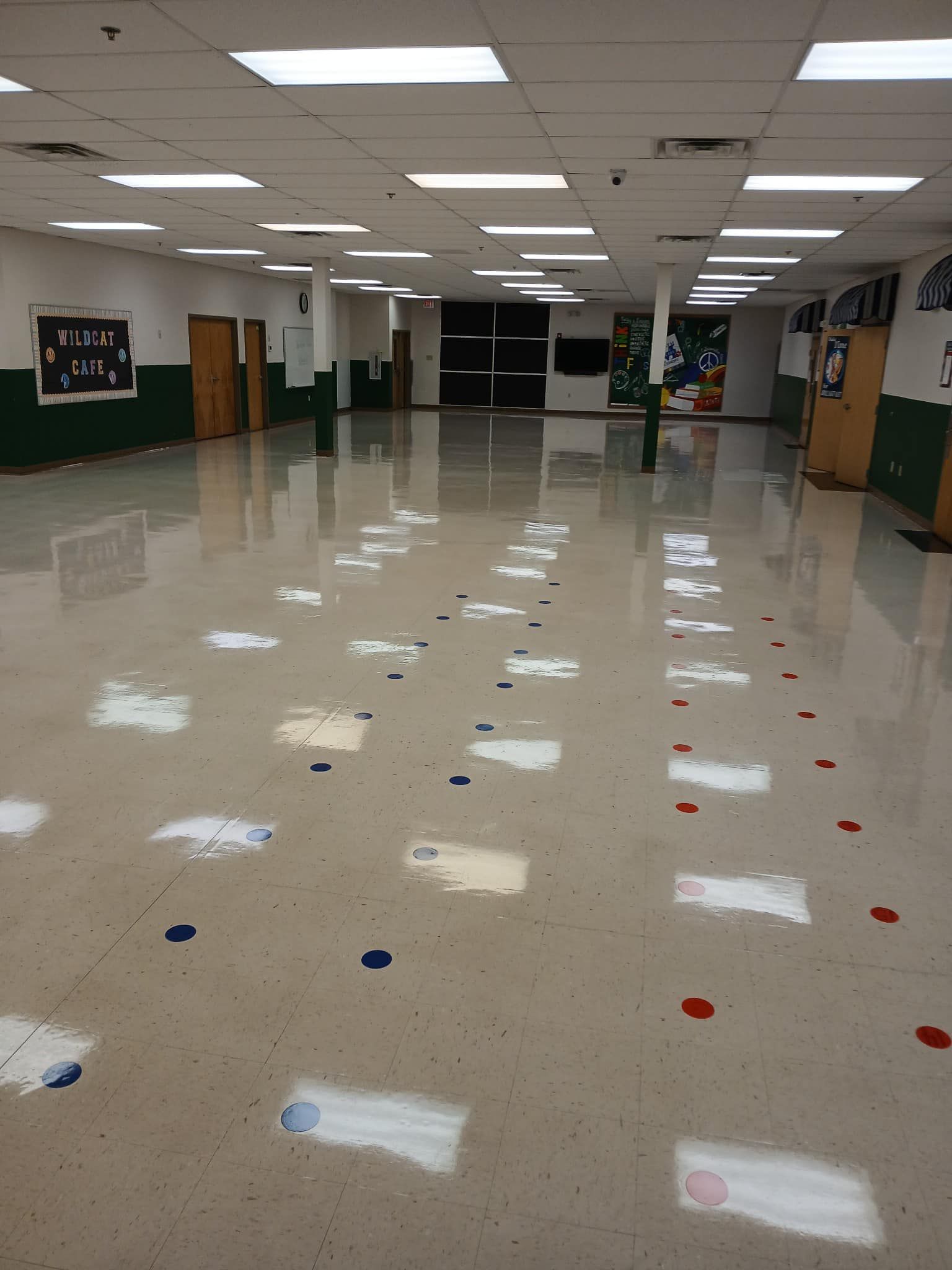 Large, empty room with white floor and ceiling. Colored markers are scattered throughout the floor.