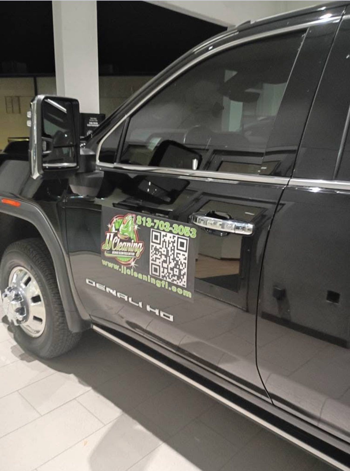 Black GMC Denali HD truck with business logo on the side, parked indoors.