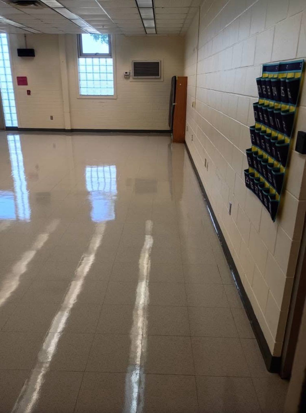 Long, empty hallway with shiny floor and yellow wall-mounted cubbies.