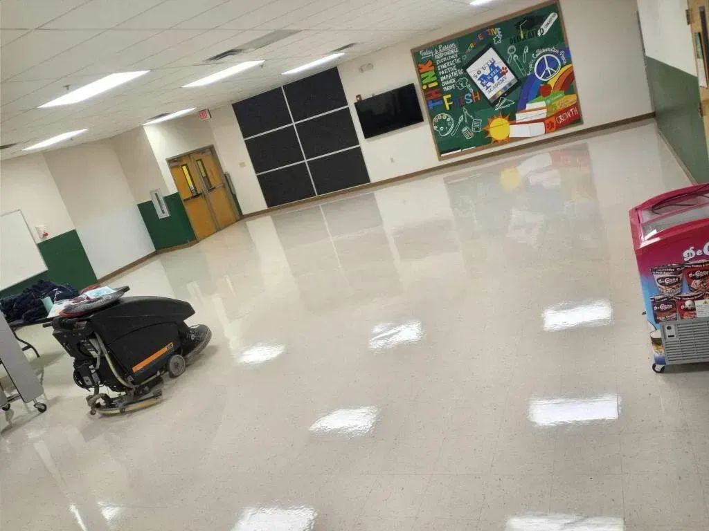 School hallway with a floor cleaning machine, colorful chalkboard, and a snack vending machine.