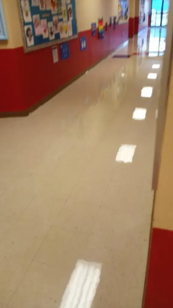 School hallway with bright floor, red wall trim, and bulletin board.