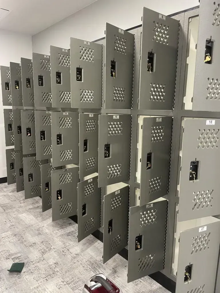 Row of grey metal lockers in a room with light-colored flooring and walls.