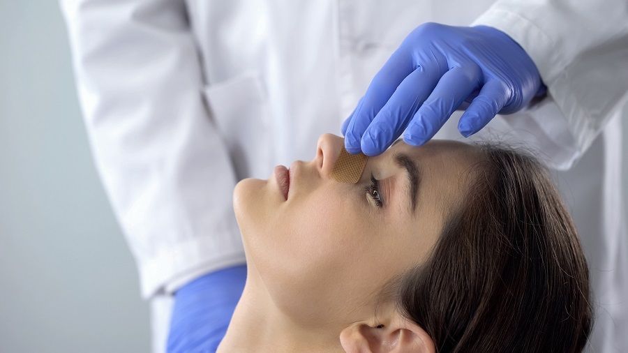 surgeon touching patient's bandaged nose