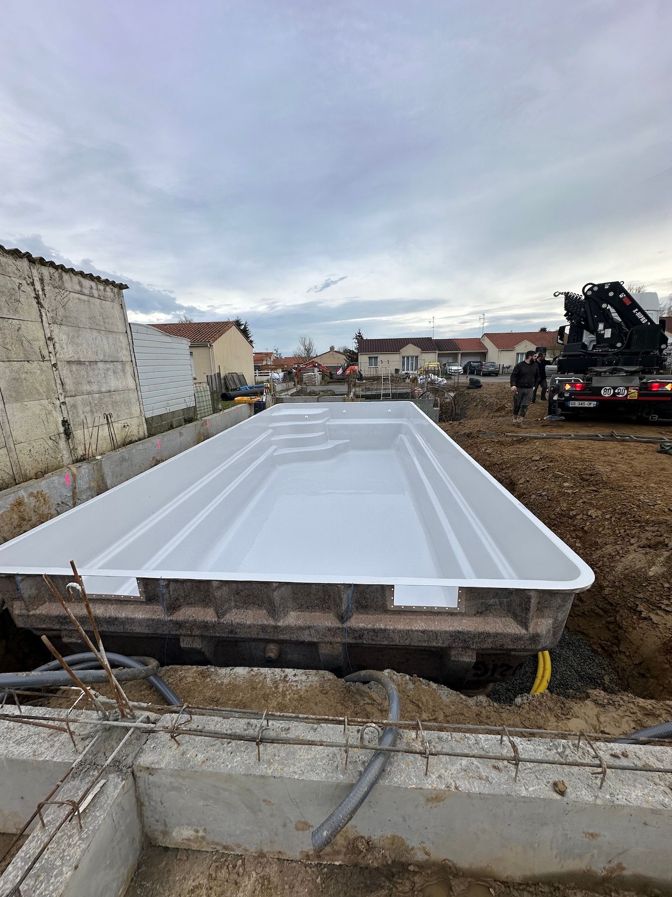 Une grande piscine blanche est en cours de construction dans un champ de terre.