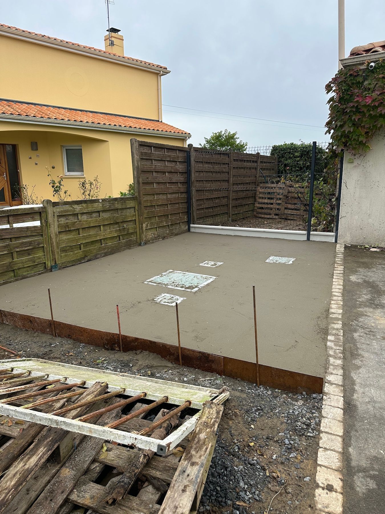 Une allée en béton est en cours de construction devant une maison.
