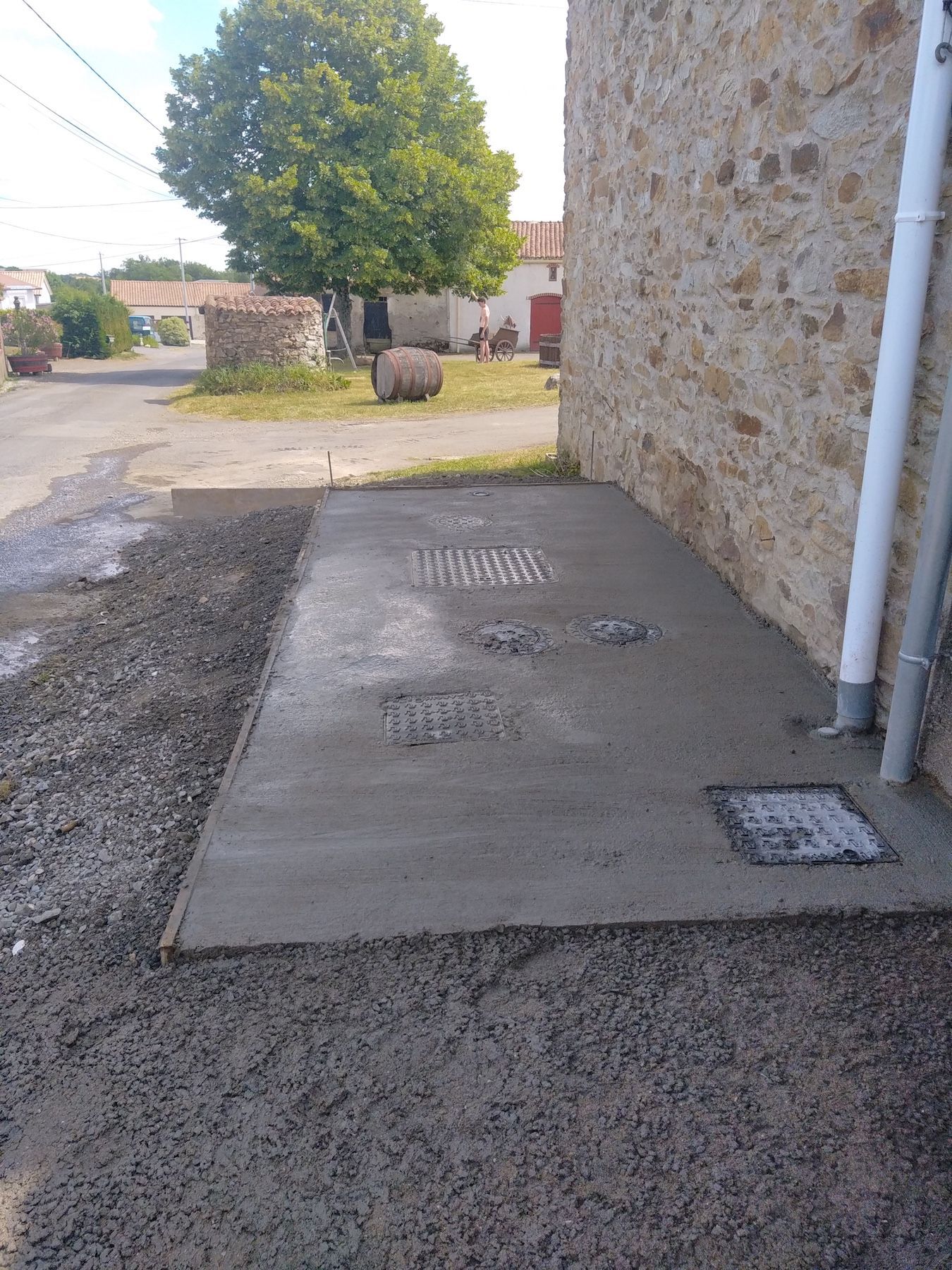 Une passerelle en béton est en cours de construction devant un bâtiment en pierre.