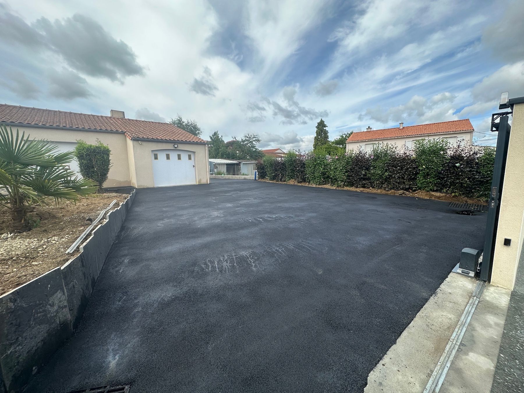 Une allée menant à une maison avec un garage en arrière-plan.