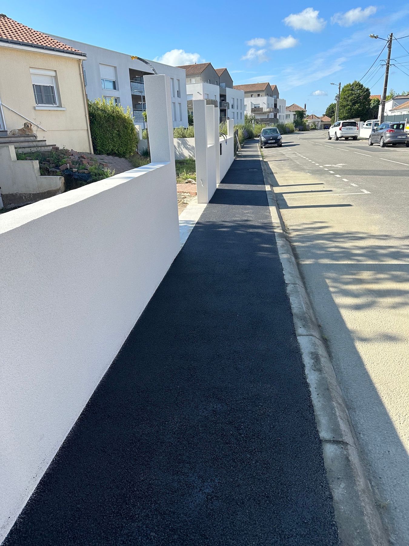 Un trottoir le long d'une rue avec un mur blanc.