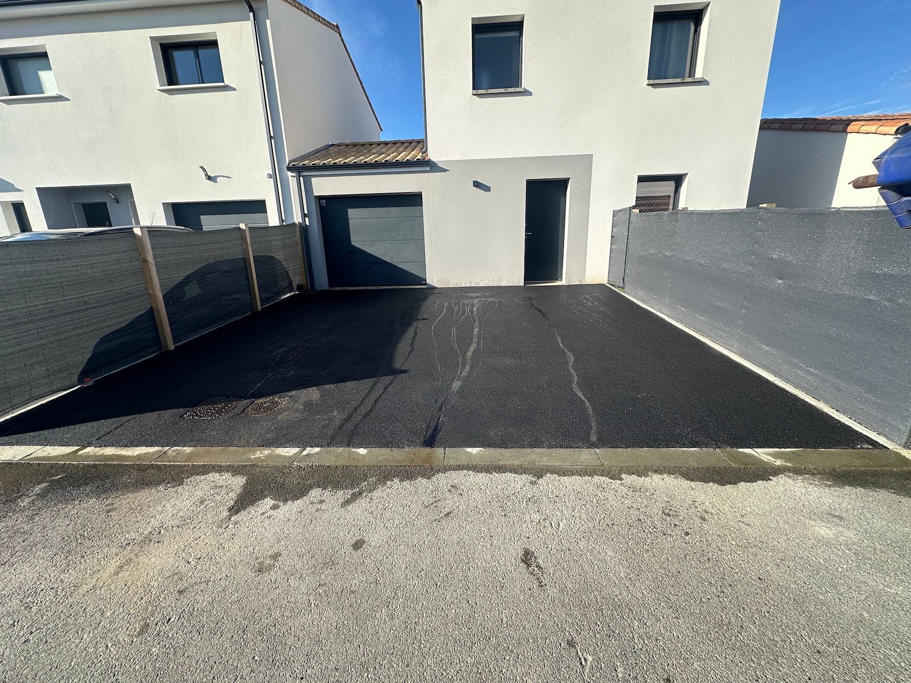 Une maison blanche avec une clôture noire et une allée noire