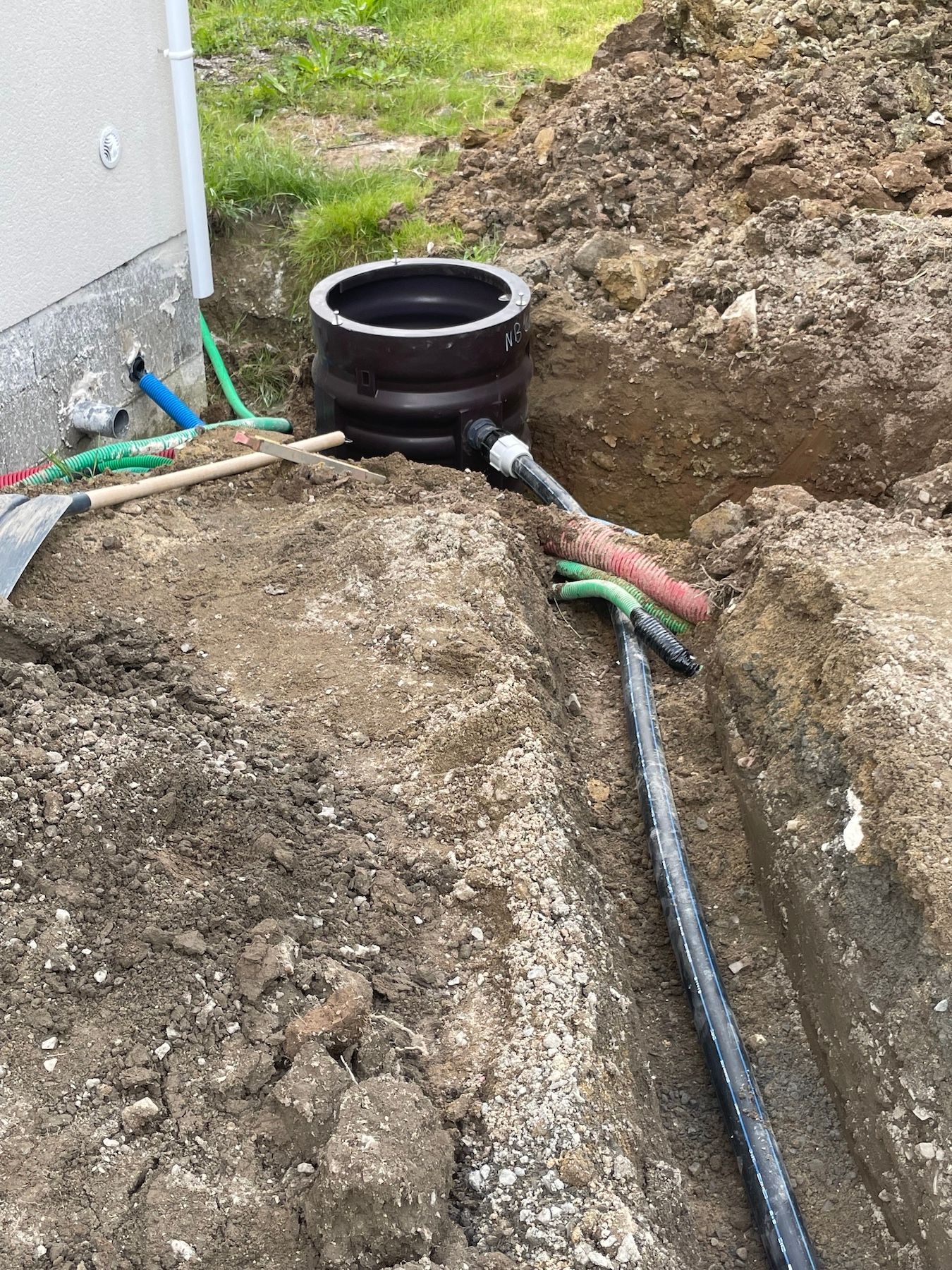 Un tuyau est en train d'être installé dans la terre à côté d'une maison.
