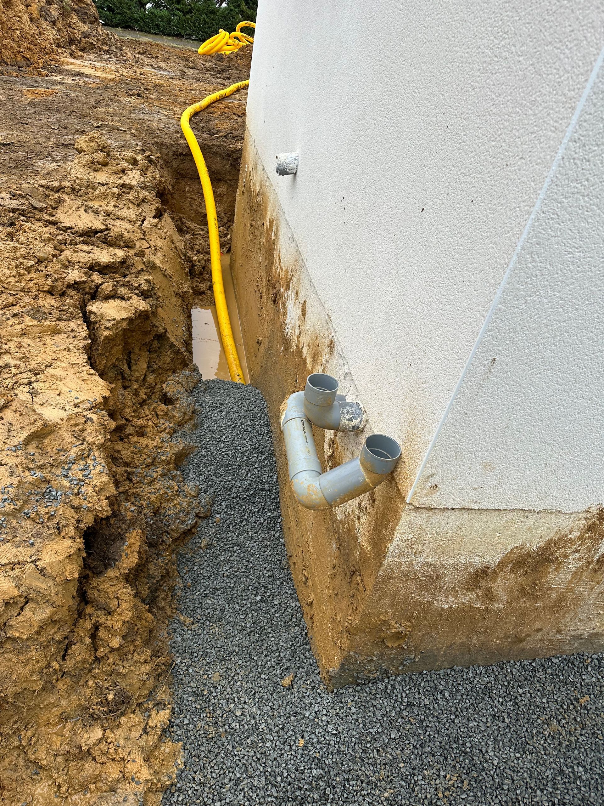 Un tuyau d'évacuation est en cours d'installation sur le côté d'un bâtiment.