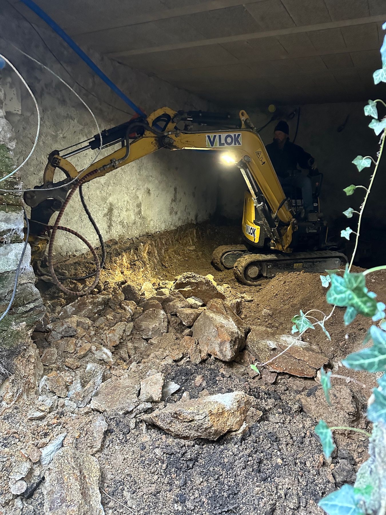 Une excavatrice jaune creuse un trou dans le sol.