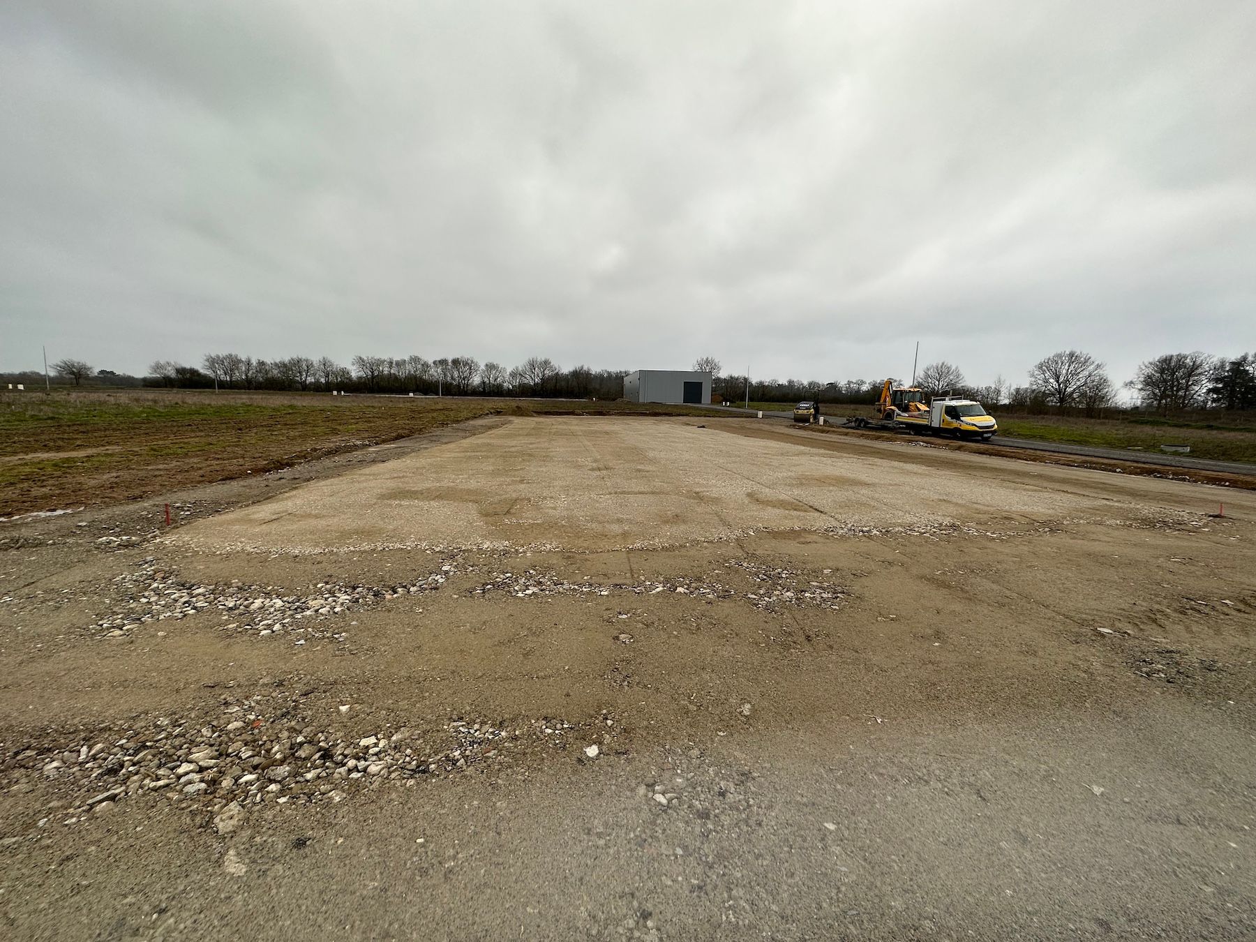 Un chemin de terre traversant un champ avec un bâtiment en arrière-plan.