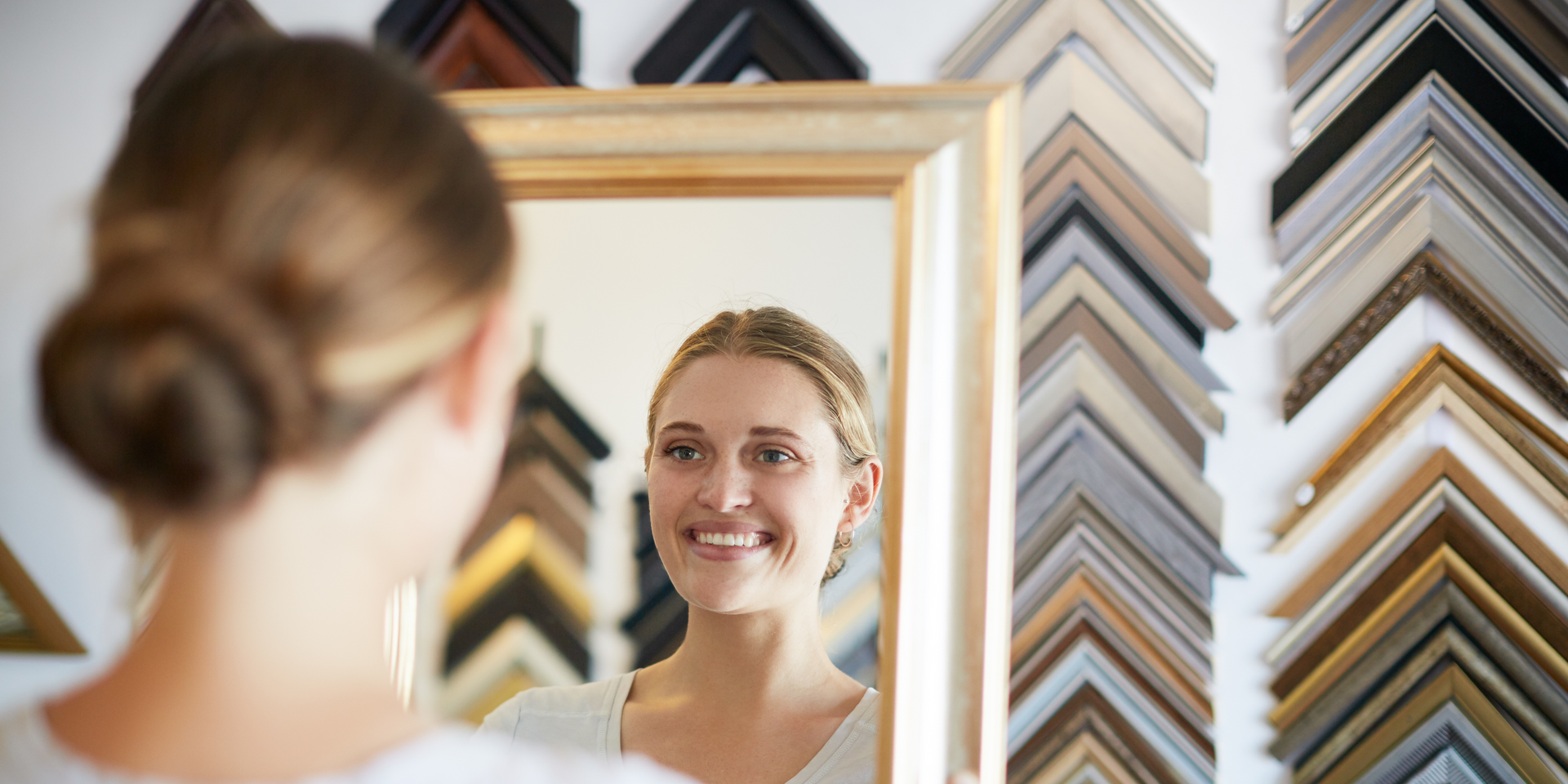 A woman is looking at her reflection in a mirror.