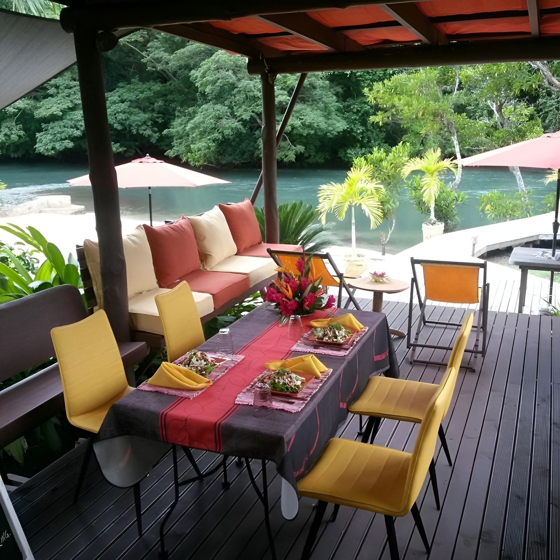 A table and chairs on a deck with a river in the background