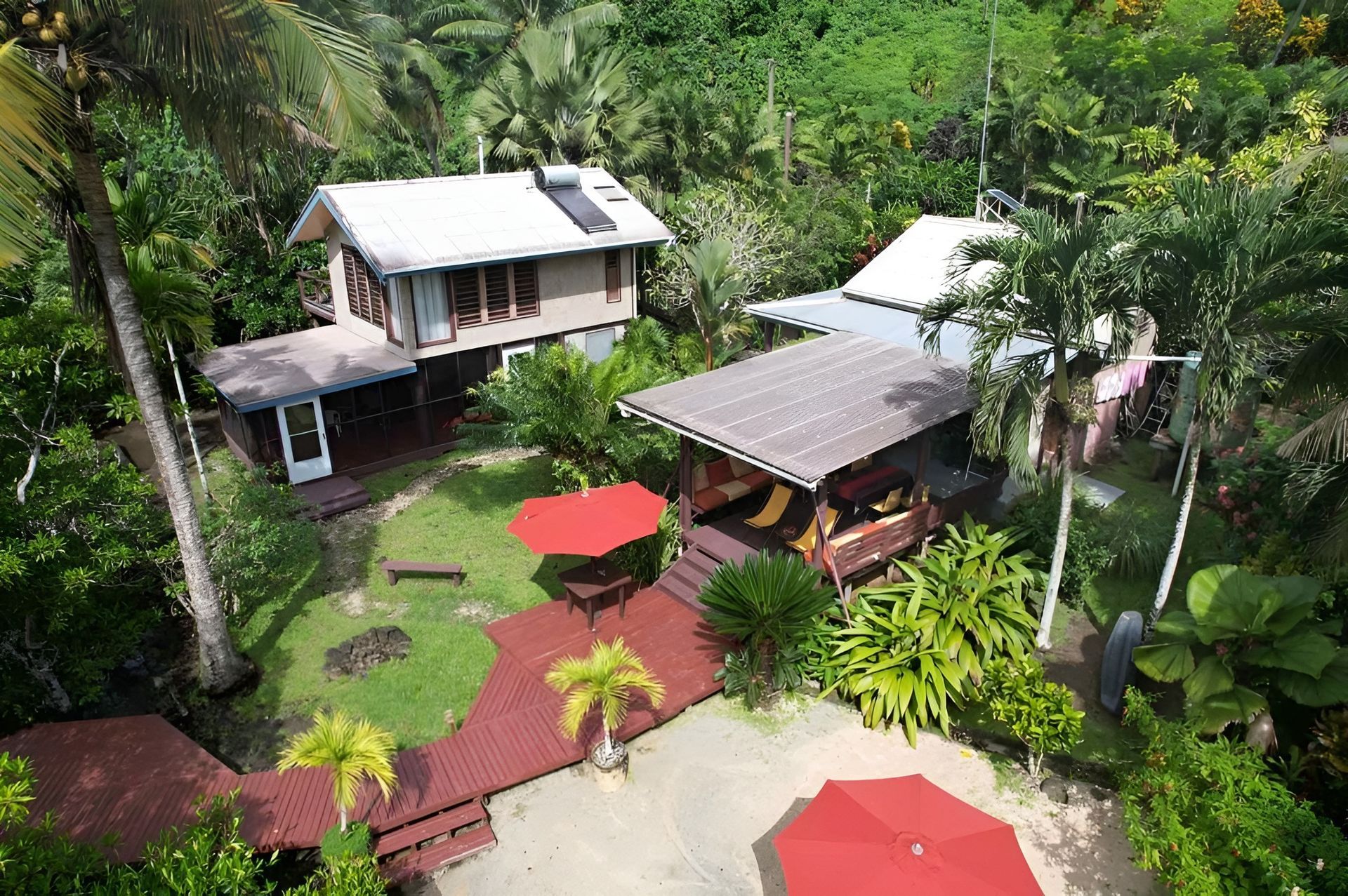 An aerial view of a house in the middle of a lush green forest