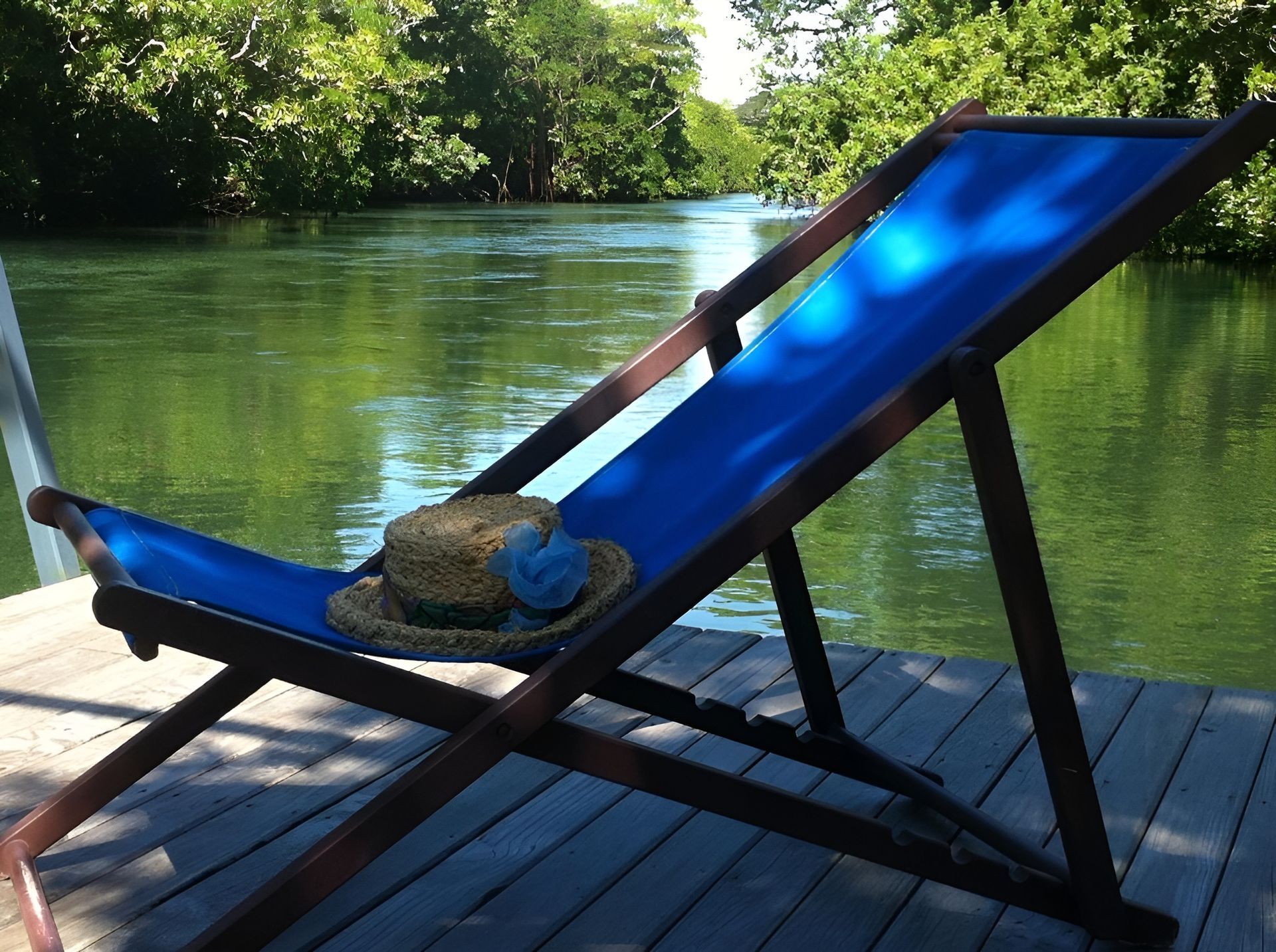 A blue lawn chair with a straw hat on it