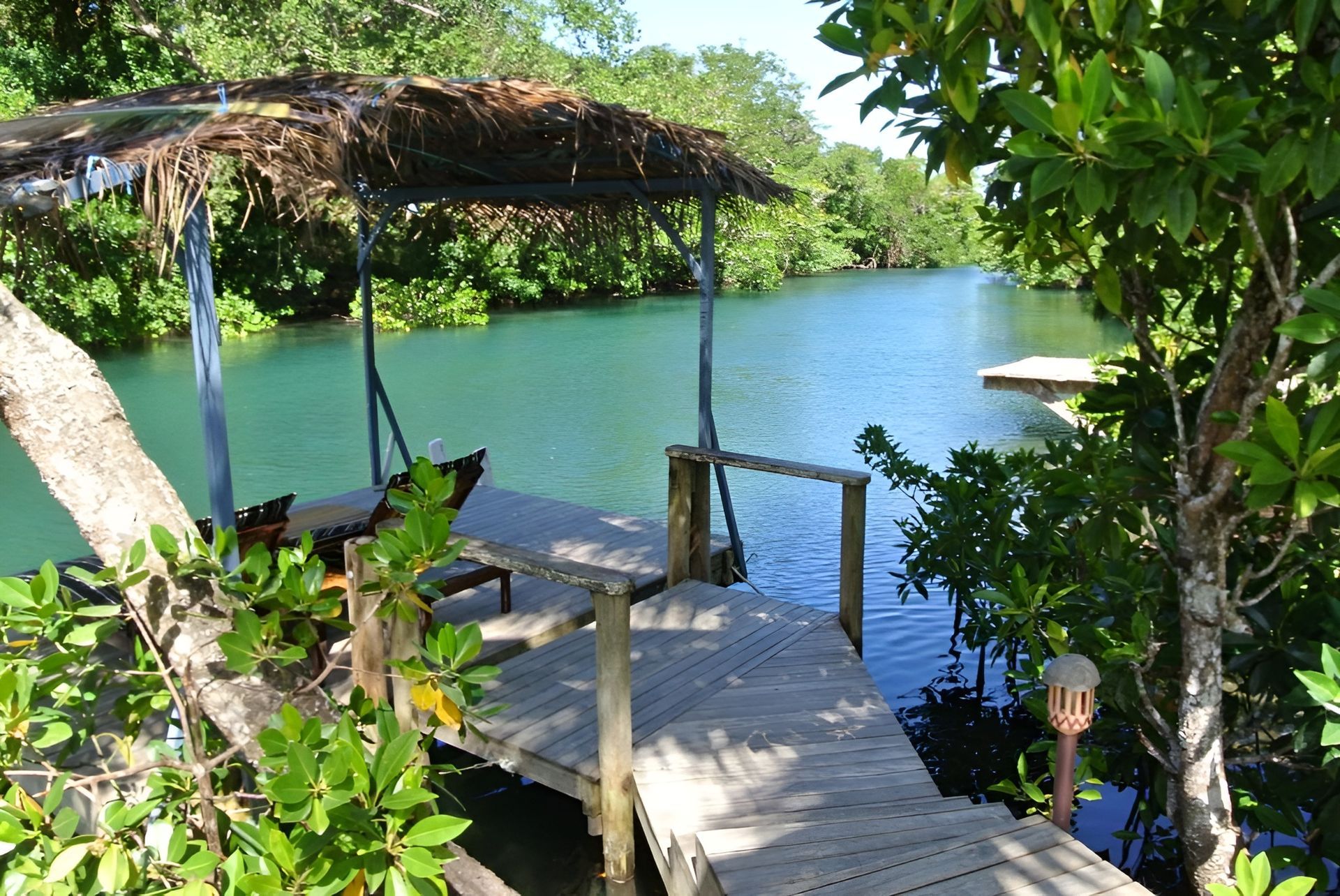A dock with a thatched roof overlooking a body of water