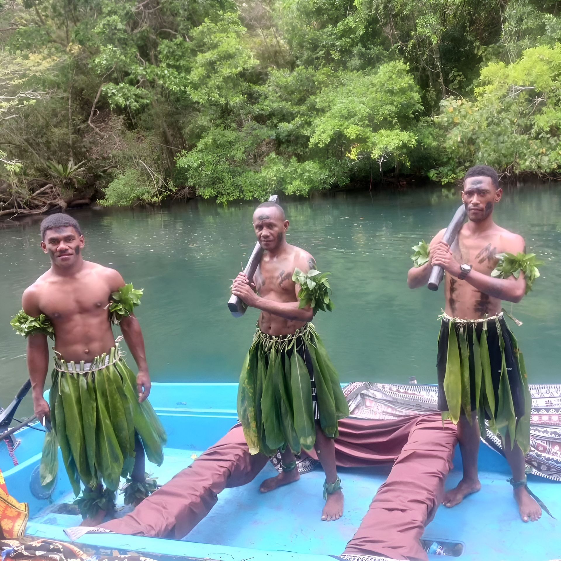 Three men in green skirts are standing on a boat