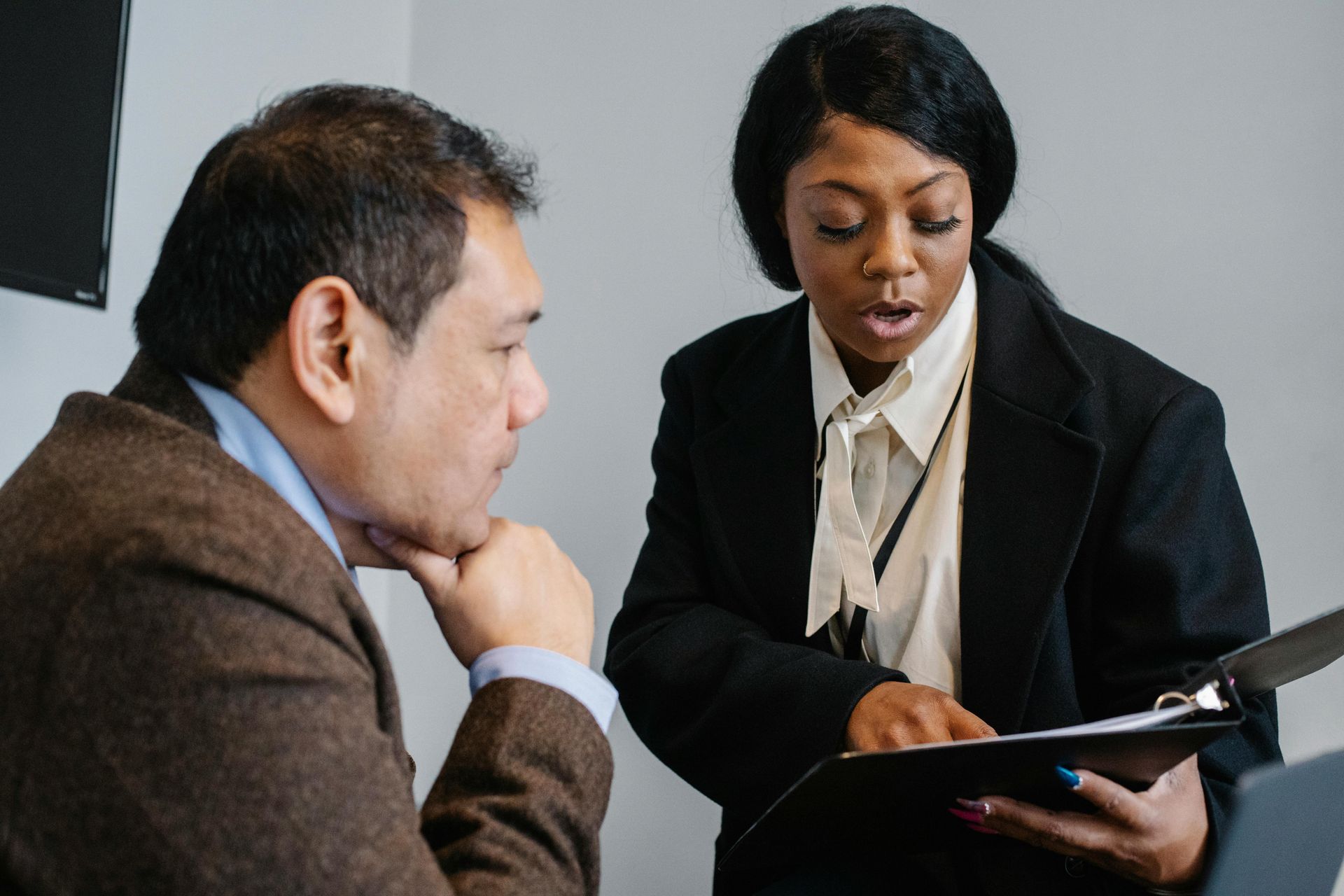 Two business professionals in suits reviewing documents, discussing strategy.