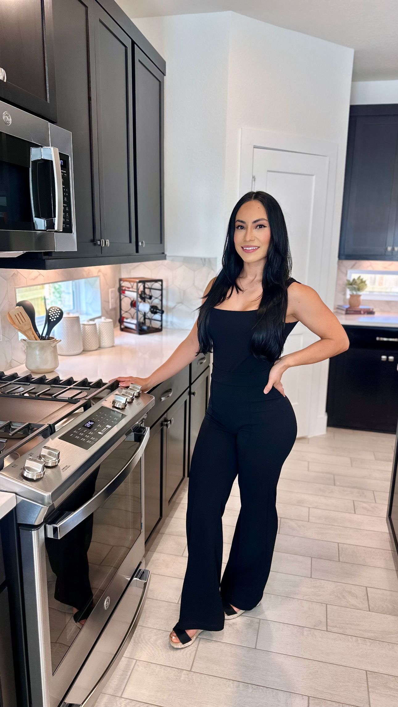 A woman is sitting at a desk with a laptop and a vase of flowers.