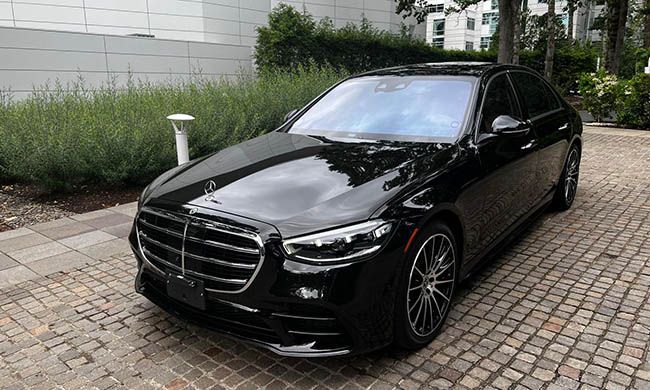 A black mercedes benz s class is parked in a driveway.