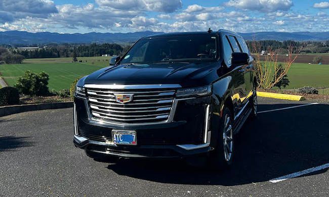 A black cadillac escalade is parked in a parking lot.