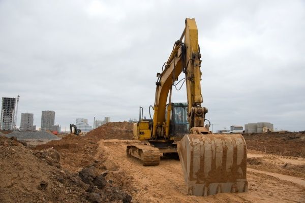 A yellow excavator is moving dirt on a construction site.