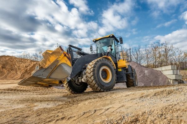 A yellow bulldozer is driving through a dirt field.