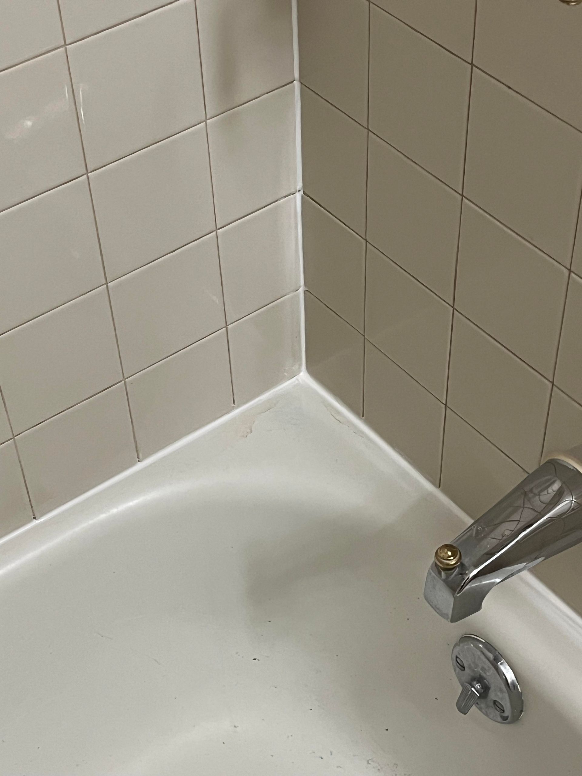 A person is applying silicone to a wooden floor.