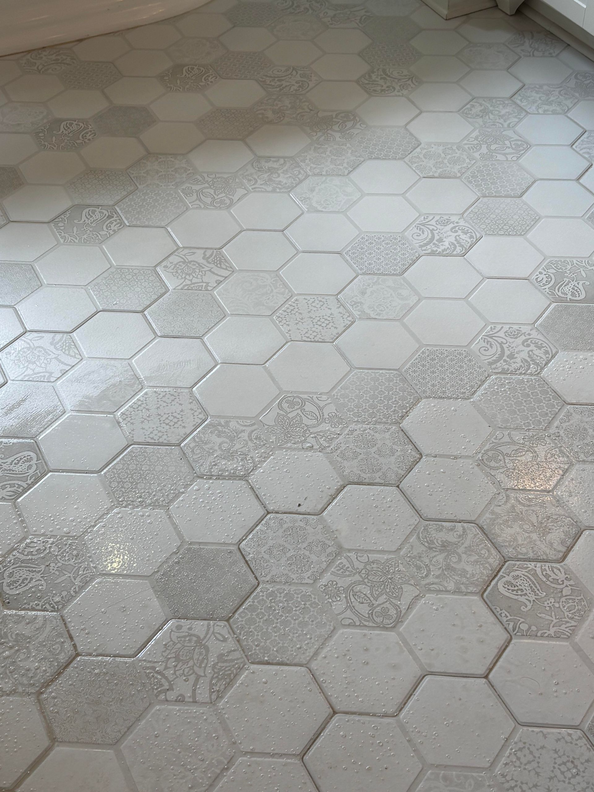 A person is applying tile adhesive to a tiled floor.
