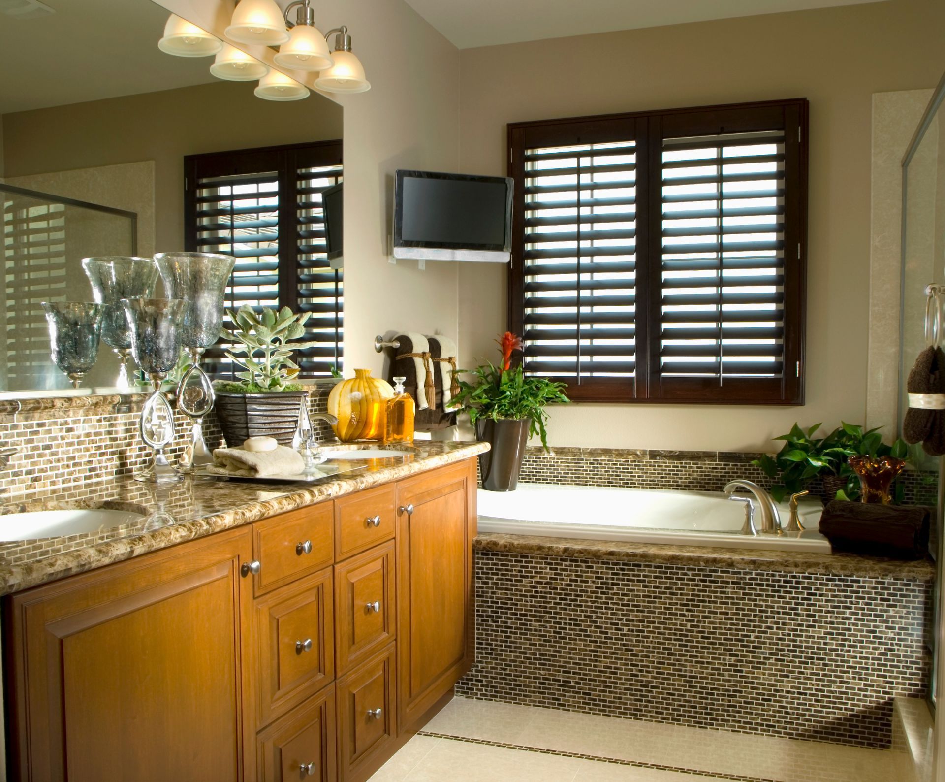 A bathroom with a sink and a tub with shutters on the windows