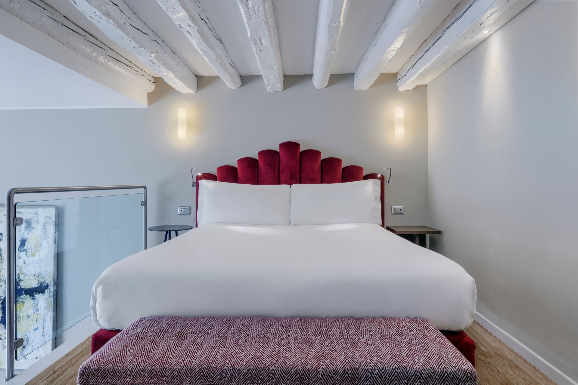 Modern gray bedroom with a purple tufted bed, wood floor, bench, and soft wall lighting