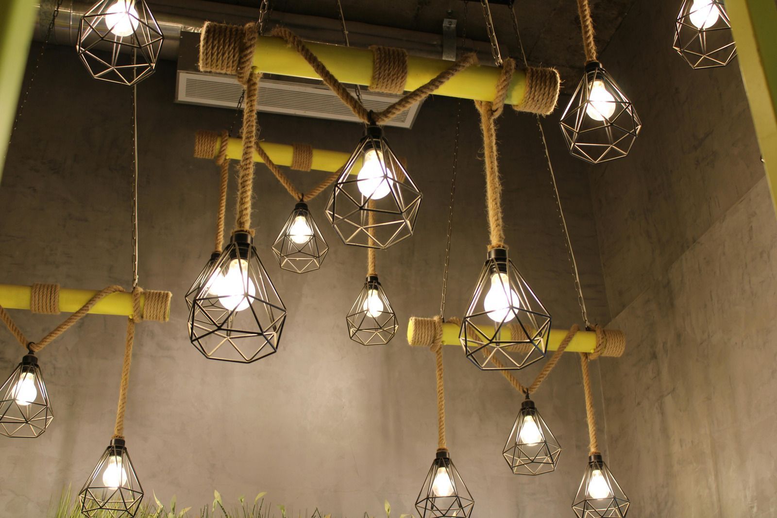 Decorative hanging lights with wire cages and exposed bulbs against a gray wall.
