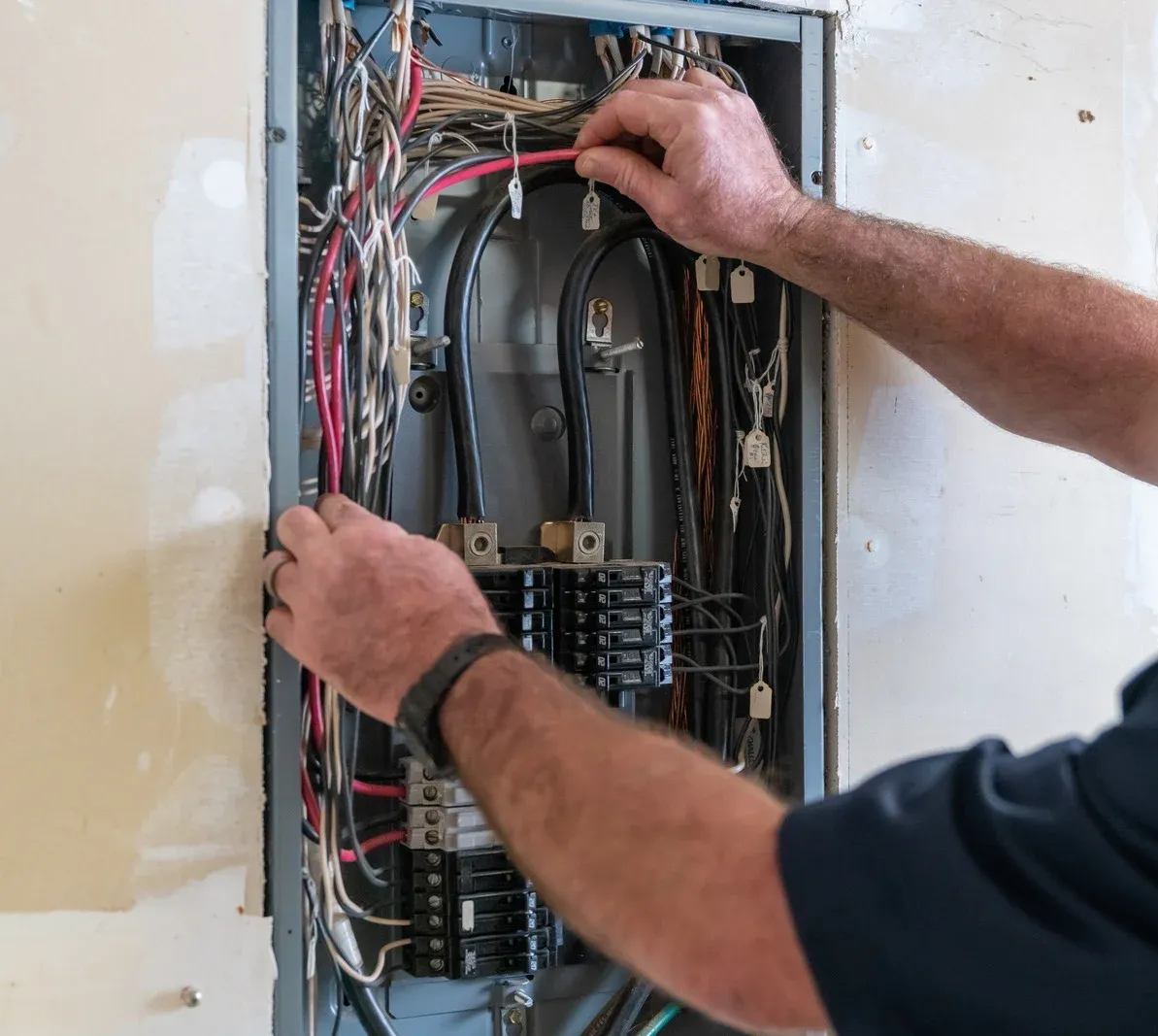 Person working on electrical panel, connecting wires.
