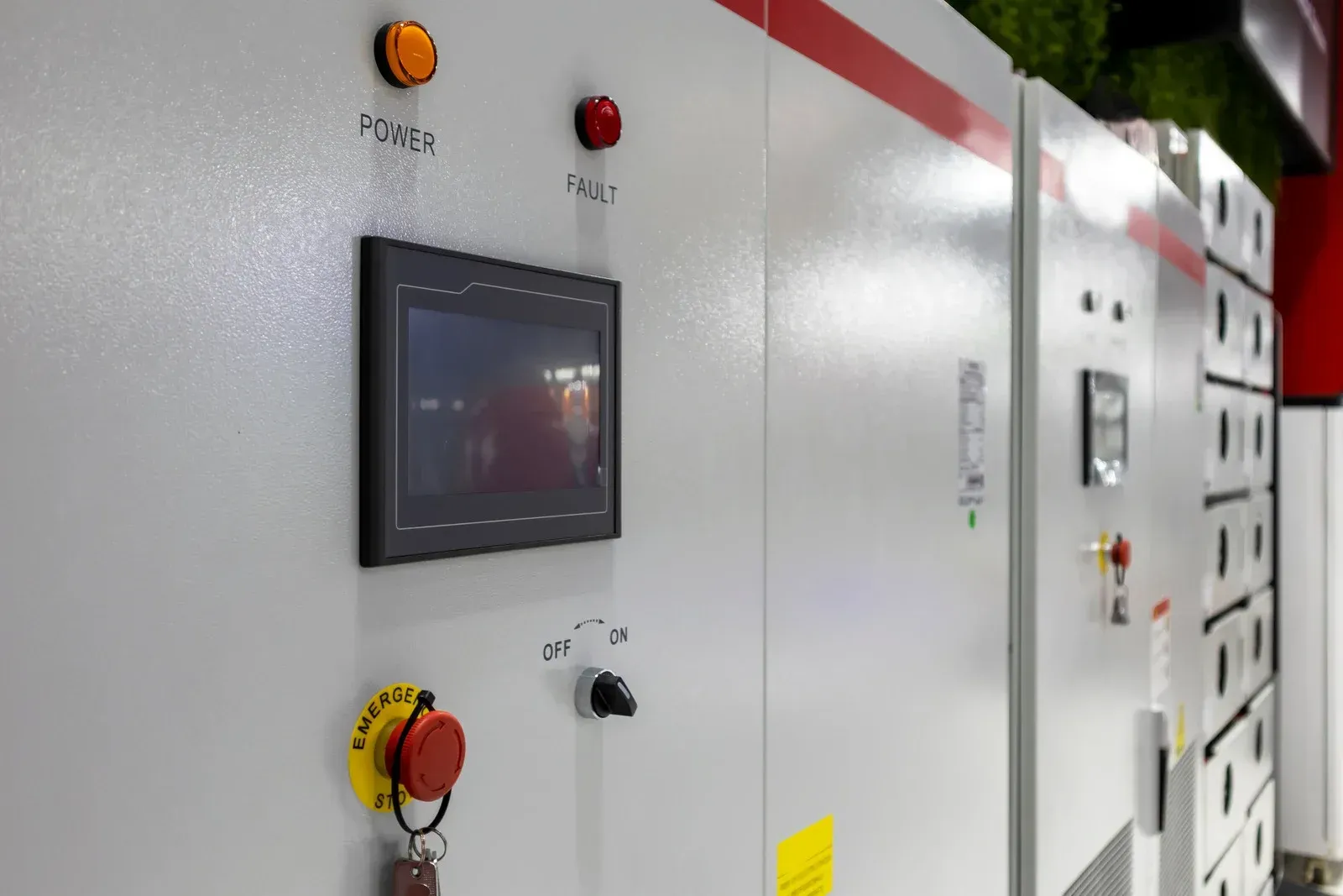 Control panel with orange and red lights, touchscreen, and emergency stop button.