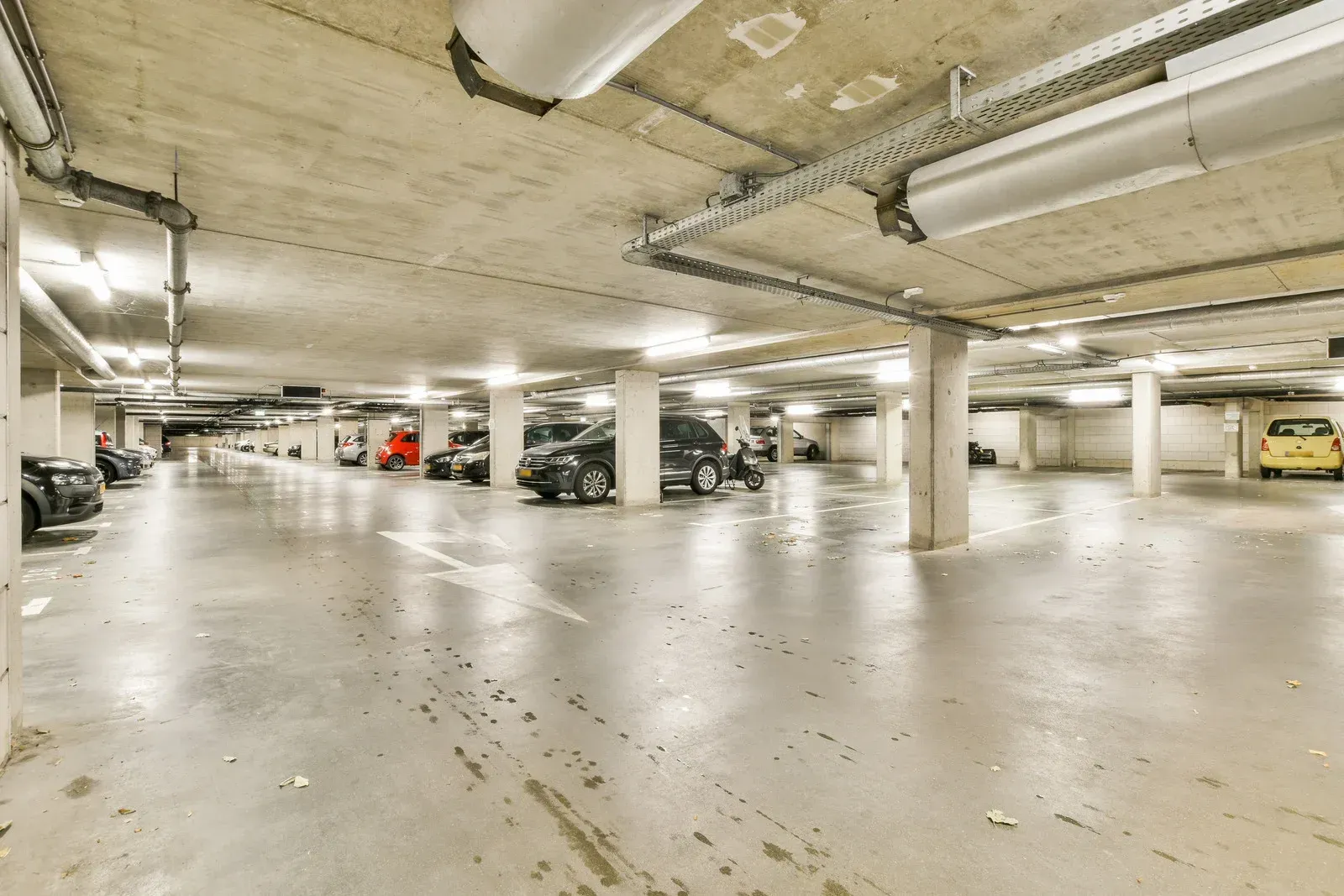 Dark, empty parking garage with support beams, and dim lighting.