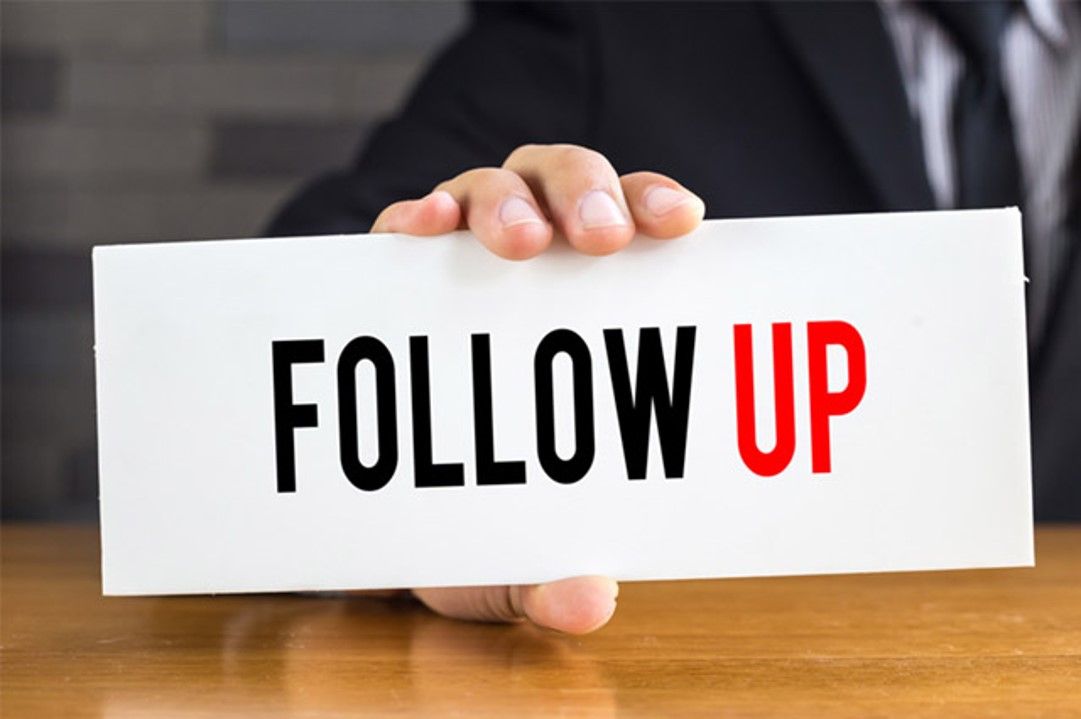 Man holding a sign in one hand that says follow up
