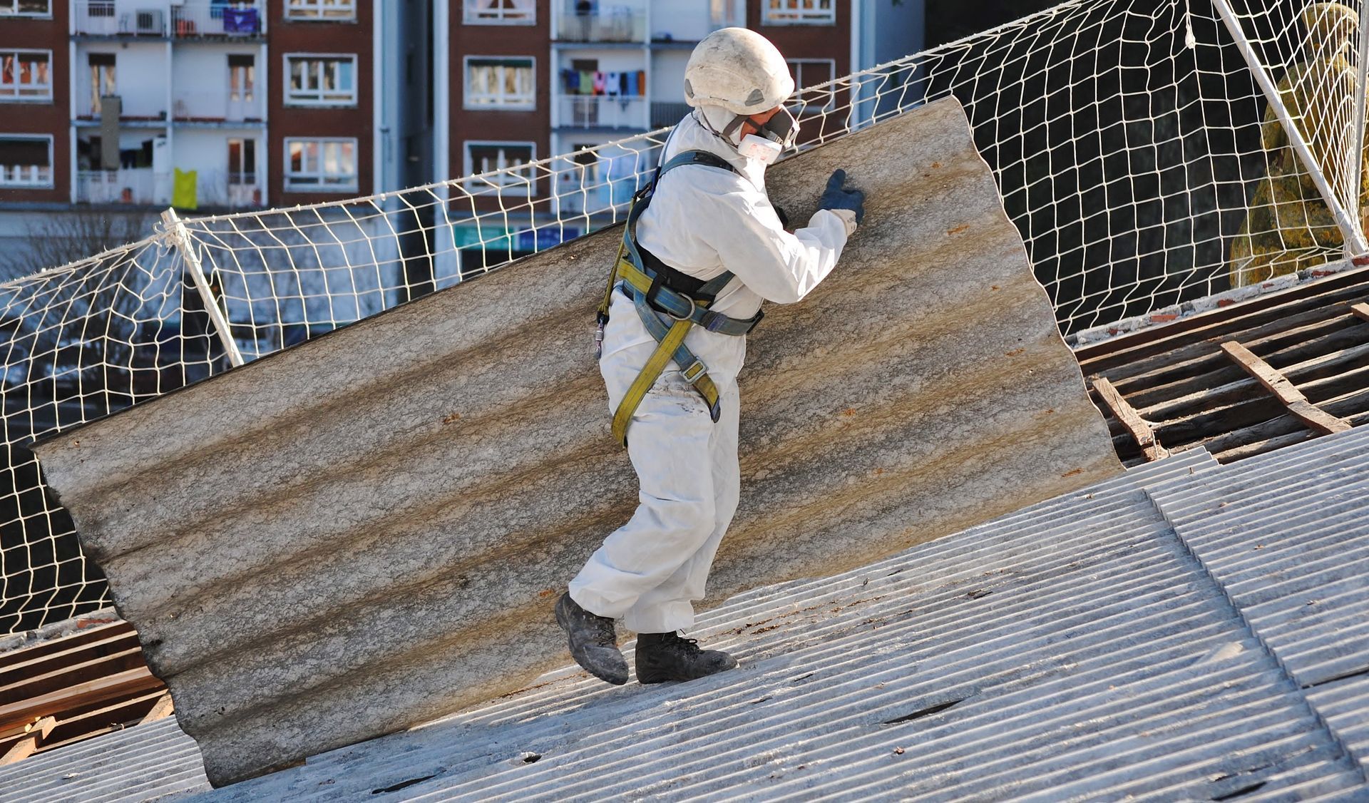 Worker in full protective gear conducting asbestos testing.
