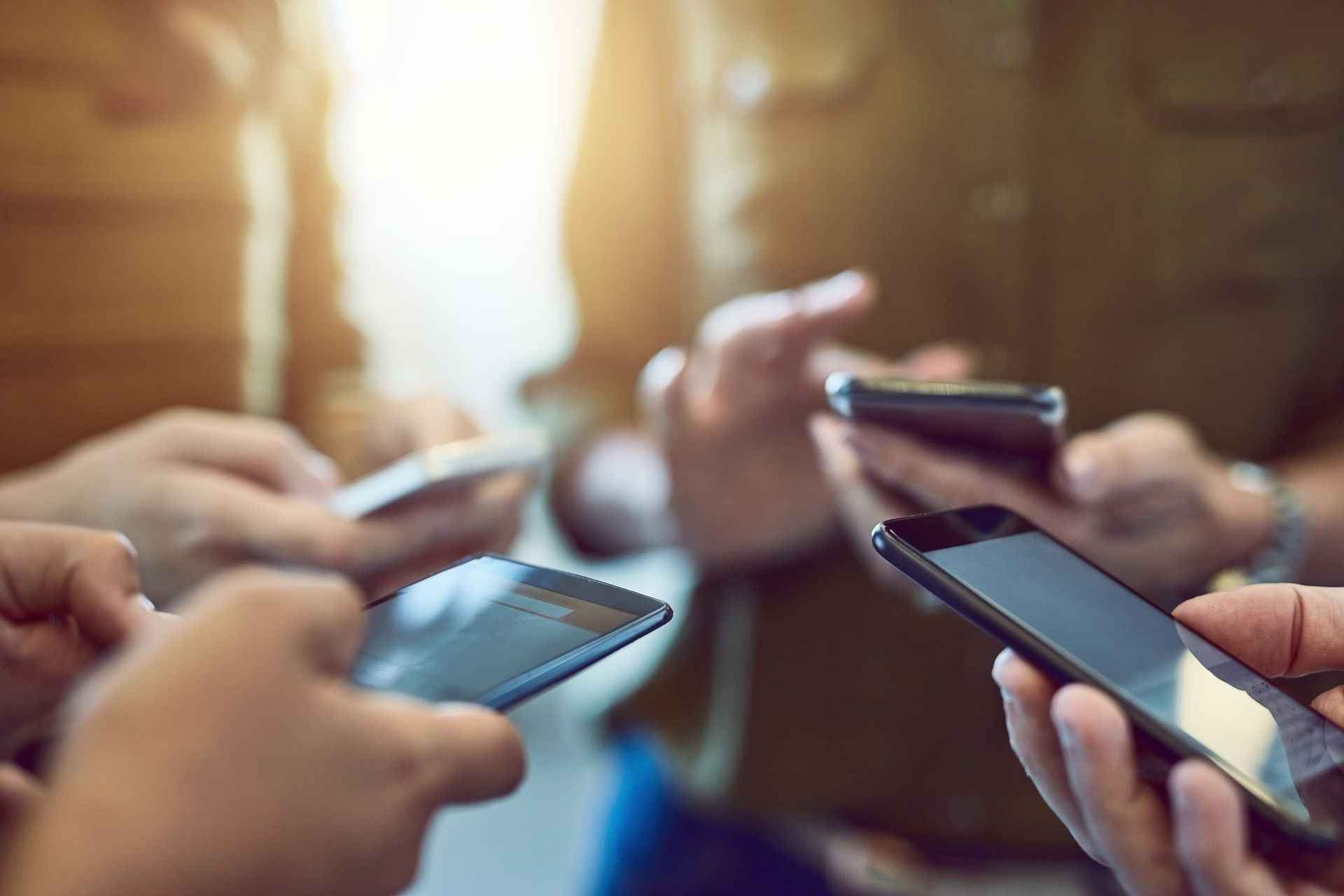 A group of people are holding cell phones in their hands.